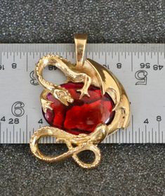 "Bronze Dragon Pendant with Red Paua Shell. This fierce little dragon clutches her special horde of red paua shell, challenging all comers. Paua shell is one of the most vibrantly colored shells used in jewelry. It is often dyed to intensify the natural iridescence of the shell. Paua shell is harvested from New Zealand and is almost always epoxy-coated to protect the relatively soft (3.5 Moh's Scale) surface of the shell. The shell used in my paua shell studs is dyed and is color-stable. Your li Unique Red Cabochon Jewelry, Red Polished Finish Collectible Jewelry, Red Enamel Collectible Jewelry, Collectible Red Jewelry With Polished Finish, Collectible Metal Jewelry With Dragon Design, Red Fantasy Metal Jewelry, Fantasy Red Metal Jewelry, Nickel-free Red Themed Jewelry, Nickel-free Themed Red Jewelry