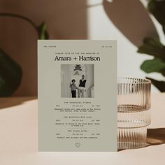 a wedding program sitting on top of a table next to a glass vase and potted plant