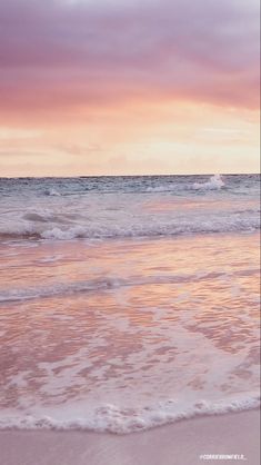 a person walking on the beach with a surfboard in their hand as the sun sets