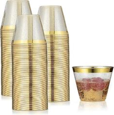 a set of four gold colored glasses and a cup