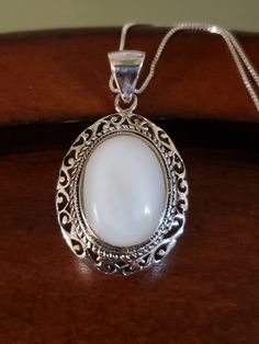 "Beautiful natural MOTHER-OF-PEARL necklace. The 18x14mm oval white Mother of Pearl is surrounded by an intricate, layered bezel setting. It almost looks like a cake from the side🤭 The large bale is hinged, and will certainly accommodate other chains too. Pendant measures 1.5\" long including the bale, and 22mm across. All Sterling Silver, weighs 9.3 grams 18\" Sterling Silver box chain Hallmarked 925 THAILAND (with maker's mark) Brand New Contact me with any questions" Oval Filigree Necklaces For Anniversary, Classic Oval Necklace With Intricate Design, Ornate Oval Pearl Pendant Jewelry, Ornate Oval Cabochon Necklaces, White Oval Necklace With Intricate Design, White Oval Link Necklace For Anniversary, White Necklace With Intricate Round Design, White Round Necklace With Intricate Design, Classic White Oval Link Jewelry