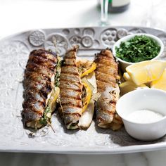 grilled fish with lemons and herbs on a white platter, ready to be eaten