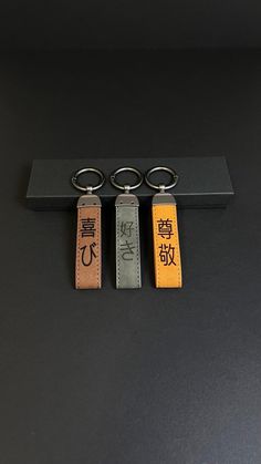 three keychains with chinese characters on them sitting on a black surface next to each other