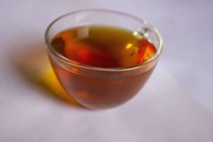 a glass filled with liquid sitting on top of a white tablecloth next to a yellow object