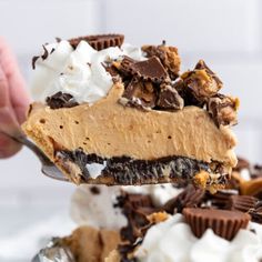 a person is holding a fork full of ice cream and chocolate pie with whipped cream on top