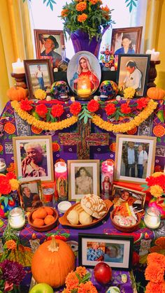 a table topped with pictures and pumpkins next to framed pictures, candles and flowers