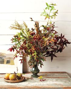 a vase filled with lots of different types of flowers next to some fruit on a table