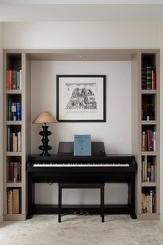 there is a black piano in the corner of this room with bookshelves and a lamp