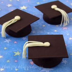 four graduation caps with white piping on them sitting on a blue background and stars