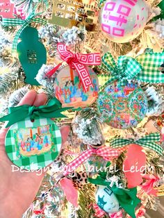 someone is holding up some ornaments in front of a christmas tree with other decorations on it