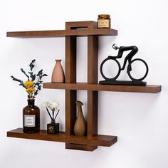 three wooden shelves with vases, bottles and other items on them against a white wall