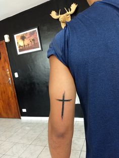 a man with a cross tattoo on his arm in a room next to a door