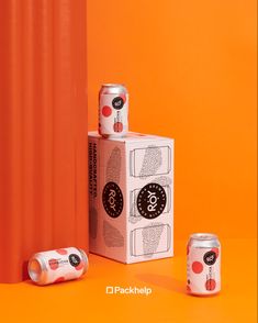 three cans of soda are stacked on top of each other in front of an orange background