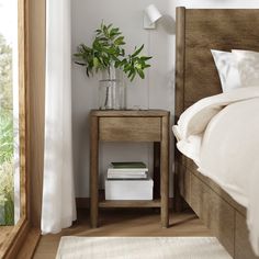 a bed room with a neatly made bed and a plant in a vase on the nightstand