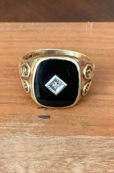 Vintage Men's 10k Yellow Gold Black Onyx Ring with Diamond Center Stone.  Substantial men's 10k yellow gold ring with black onyx face with a center diamond. The band is stamped DASON 10k. DASON is the trademark by Davidson & Sons Jewelry. Co., Inc. in New York. The ring face measures approx. a bit over 5/8" L x 1/2" W.   The size of the ring is 12 - 12 1/4 and can be resized by a jeweler. The onyx face has a very slight scratch which is not visible unless a bright light is shined on the face. The center diamond is approx. 1 mm which equates to .005 CT weight. The ring weighs 5.6 grams. The sides of the band features scroll marks. This ring belonged to my husband's father and has been in the family for 70+ years. The ring will be sent insured and signature required. A wonderful vintage ring Vintage Onyx Ring For Men, Classic Black Diamond Ring With Black Enamel, Onyx Signet Ring With Black Enamel For Anniversary, Anniversary Onyx Signet Ring With Black Enamel, Heirloom Black Signet Ring, Black Signet Ring With Diamond Accents, Classic Black Diamond Ring Stamped 14k, Classic Hallmarked Black Diamond Ring, Classic Black Hallmarked Diamond Ring