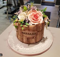 a birthday cake made to look like a wooden barrel with flowers on top and the words barbara written on it