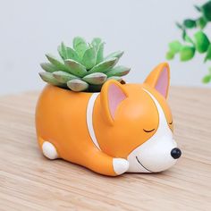 a small orange and white ceramic animal with a succulent in it's mouth