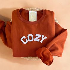 Cozy up with our Cozy Crewneck Sweatshirt this fall season! - Sweatshirt is super soft and comfy! ♡ - Sweatshirt composition: 50% cotton, 50% polyester - All our sweatshirts run a unisex fit. They are naturally oversized, so we normally recommend your true size. But if you like a more baggy look, we recommend sizing up. - These letters are iron-on patched and is heat pressed, not embroidered. But rest assured they've been tested and won't fall off! - Please note that crewneck brand used may vary Cozy College Sweater With Ribbed Cuffs, Cute Fleece Tops For Fall, Cozy Fleece Tops For Everyday, Cozy Everyday Fleece Top, Cute Fleece Sweater For Fall, Cozy Fall Sweater For College, Cozy Fall College Sweater, Cozy Brown Sweatshirt For Loungewear, Cozy Fit Cotton Sweatshirt