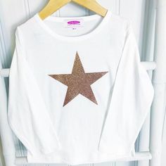 The newest addition to our Candy Bows Tshirt Collection. A Whitek cotton long or short sleeve tshirt is embellished with a vinyl large Rose Gold Super Star that shimmers in the light. Perfect for little girls to wear all year round, to any party, or just to look sassy at the weekend.  The Star is available in a variety of vinyls:Rose Gold GlitterRose Gold ShinyLeopard PrintSnakeskin PrintRainbow Oil The t-shirt is a non-personalised tshirt (personalised design available in hoodie on our website) Pink Star Print Crew Neck T-shirt, Pink Crew Neck T-shirt With Star Print, Trendy Long Sleeve Glitter Top, Pink Crew Neck Top With Star Print, Long Sleeve Cotton Tops With Glitter Print, White Glitter Print Crew Neck Top, Casual Long Sleeve Glitter Tops, Dance Hoodies, Tshirt Collection