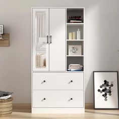 a white bookcase with drawers in the corner next to a basket and pictures on the wall