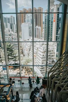 people sitting at tables in front of large windows looking out on the city below them