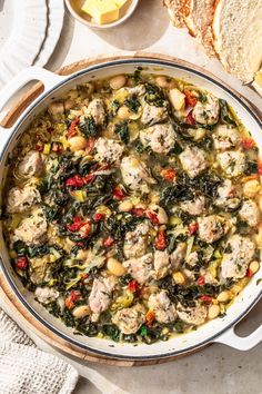 a pot filled with meat and vegetables on top of a table next to some bread