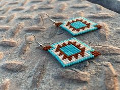 a pair of beaded earrings sitting on top of a rock