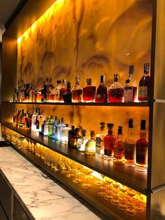 bottles and glasses are lined up on the wall in front of an illuminated display case