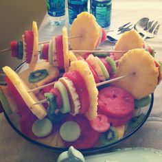 a bowl filled with different types of fruit on skewers