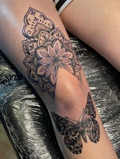 a woman's leg with a butterfly and flower tattoo design on the side of her leg