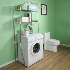 a washer sitting next to a toilet in a room with green walls and wooden floors