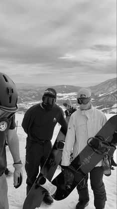 three snowboarders are walking in the snow with their boards attached to their backs