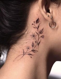 a woman's neck has a small flower tattoo on her left side behind the ear