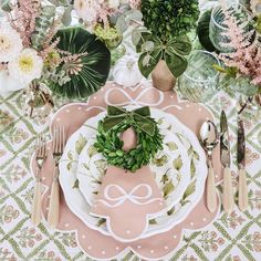 a table set with plates, silverware and flowers