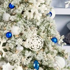 a white christmas tree with blue and silver ornaments