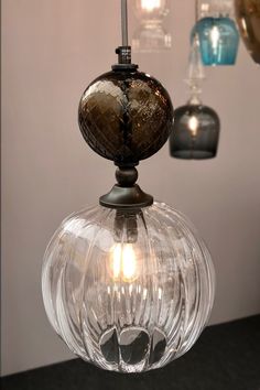 a glass light fixture hanging from the ceiling in a room with several lights on it