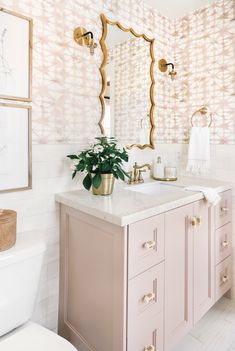 a bathroom with a sink, mirror and potted plant