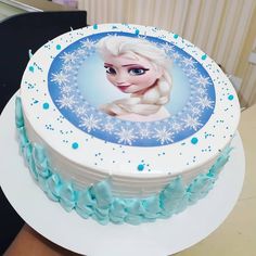 a frozen princess cake with blue frosting on it's face and snowflakes around the edges