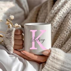 a woman holding a coffee mug with the letter k on it