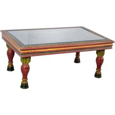 a glass top coffee table with wooden legs and red trimmings on the bottom