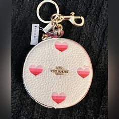 a white coin purse with pink hearts on it and a keychain hanging from the front