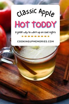 an apple hot toddy in a glass mug with cinnamon sticks and apples on the side