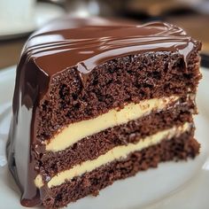 a piece of chocolate cake with white frosting and chocolate ganache on top, sitting on a plate