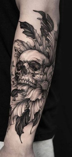 a man's arm with a skull and feathers on it