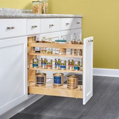 an open cabinet in a kitchen with spices and condiments on the bottom shelf