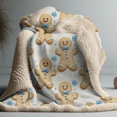 a baby blanket with gingerbreads and snowflakes on it, sitting next to a teddy bear