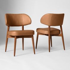 two brown chairs sitting next to each other on a white surface with one chair facing the other