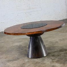 a wooden table sitting on top of a cement floor next to a white brick wall