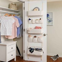 an open closet with clothes and shoes on the floor next to a white cabinet filled with baby items