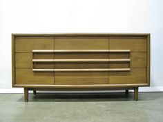 a large wooden dresser sitting on top of a cement floor next to a white wall